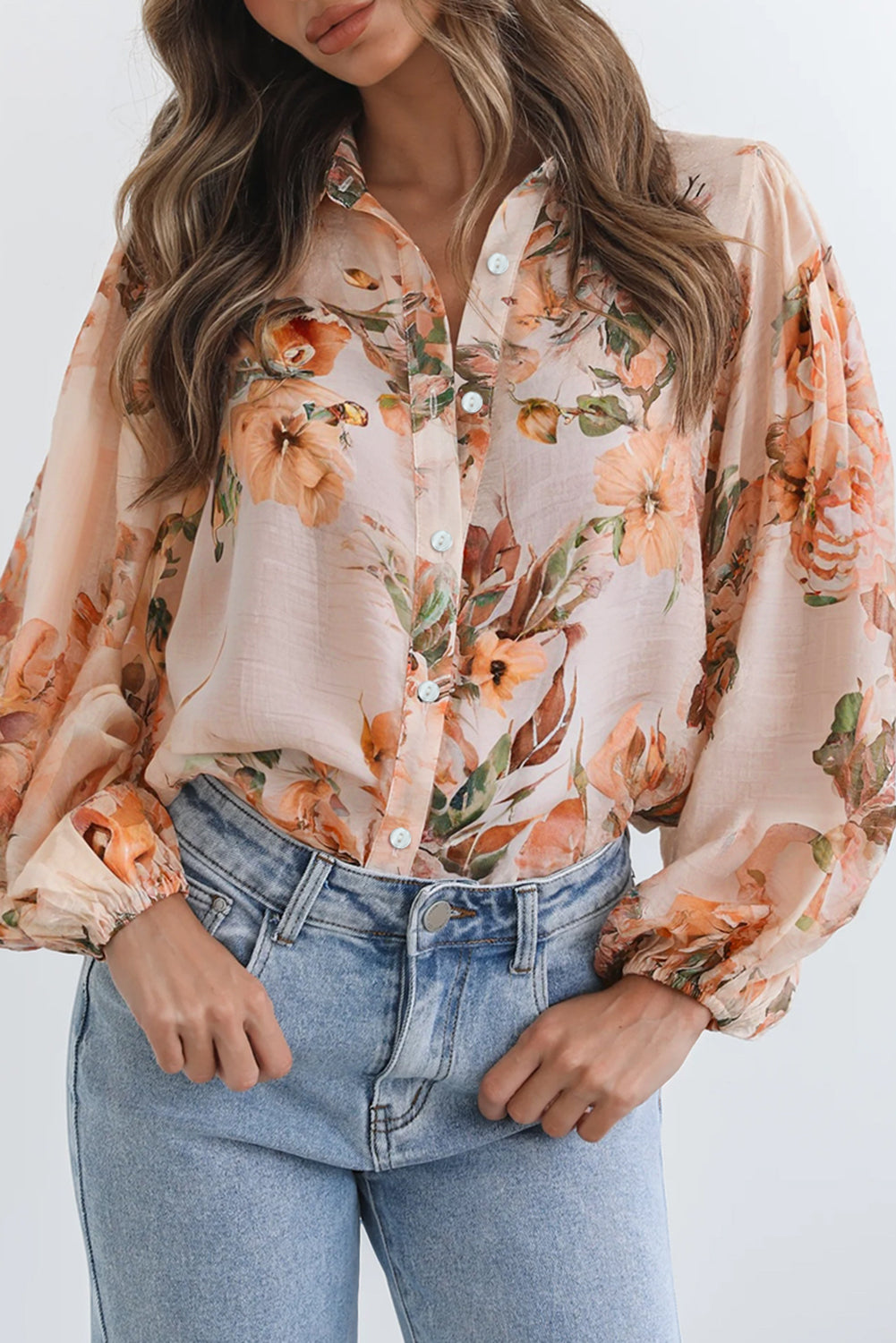 Woman wearing a floral blouse and jeans against a white background