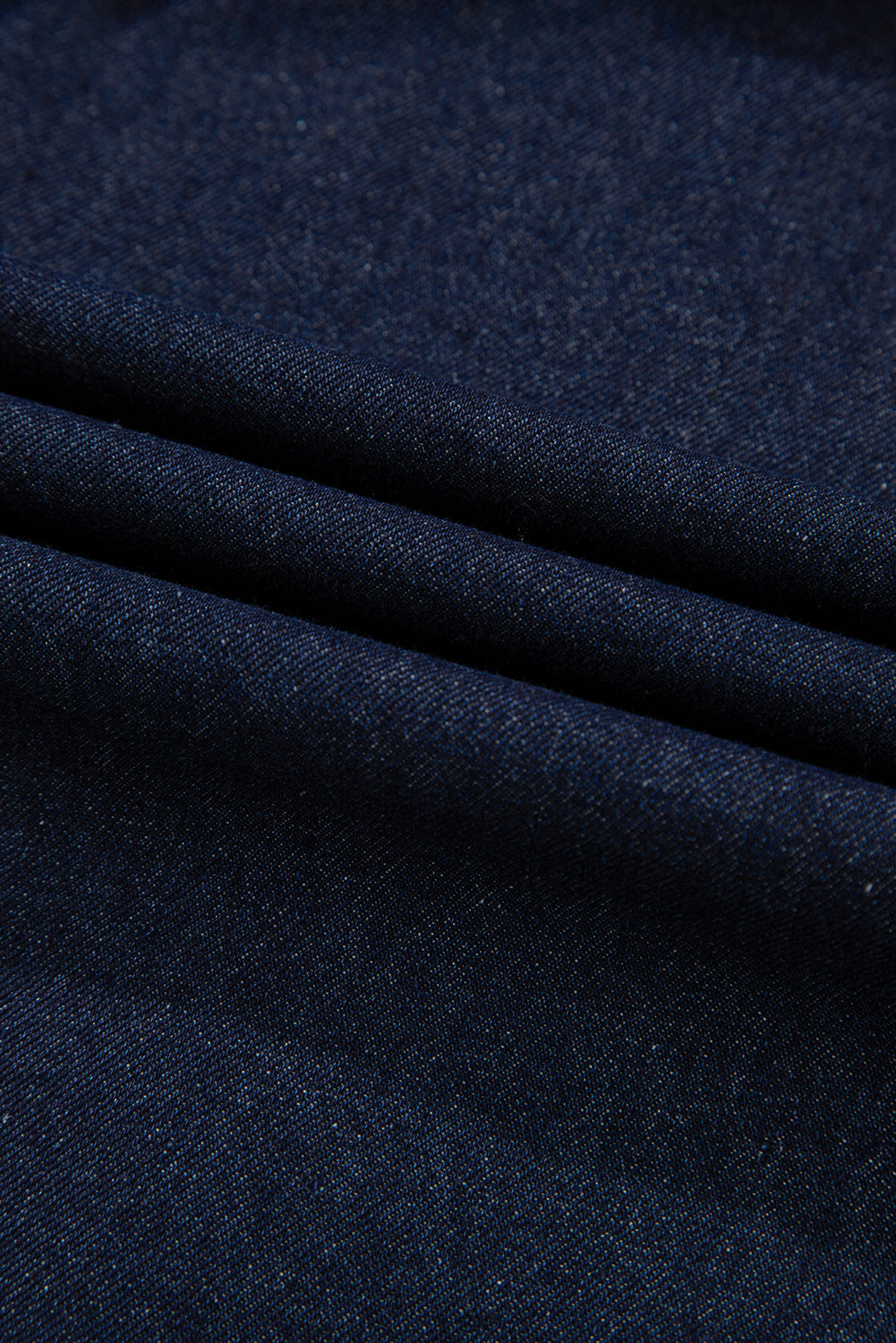 A dark blue denim flowy mini dress with short puff sleeves. Fabric view.