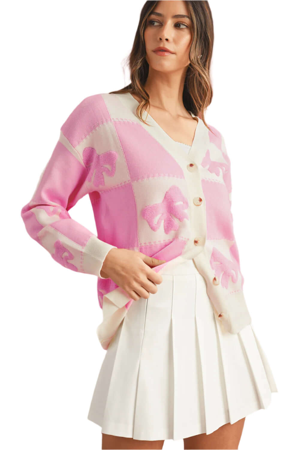 Woman wearing a pink checkered knit cardigan with palm details, styled with a white pleated skirt.