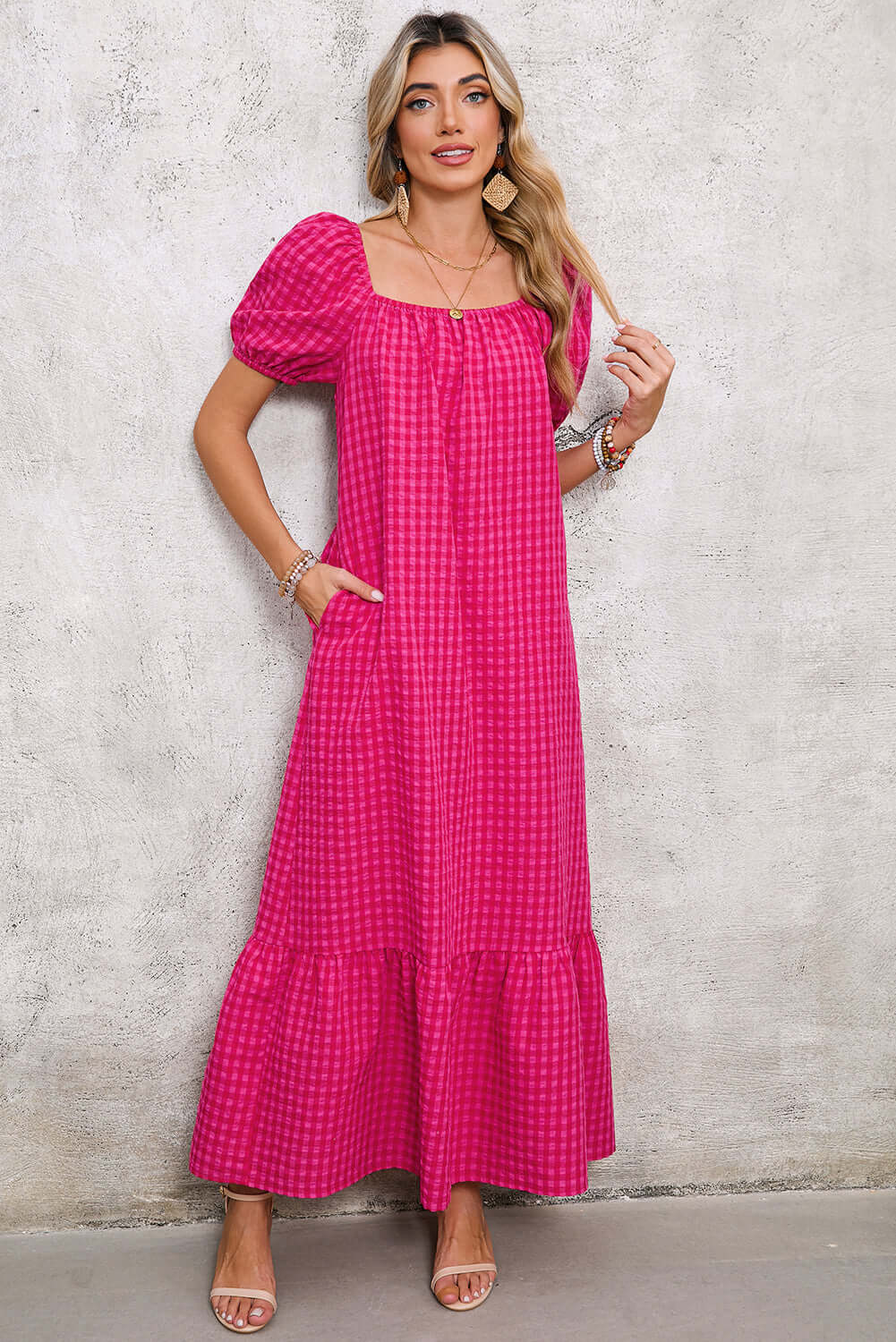 Woman wearing a rose gingham maxi dress with puff sleeves and a square neckline, styled with sandals.