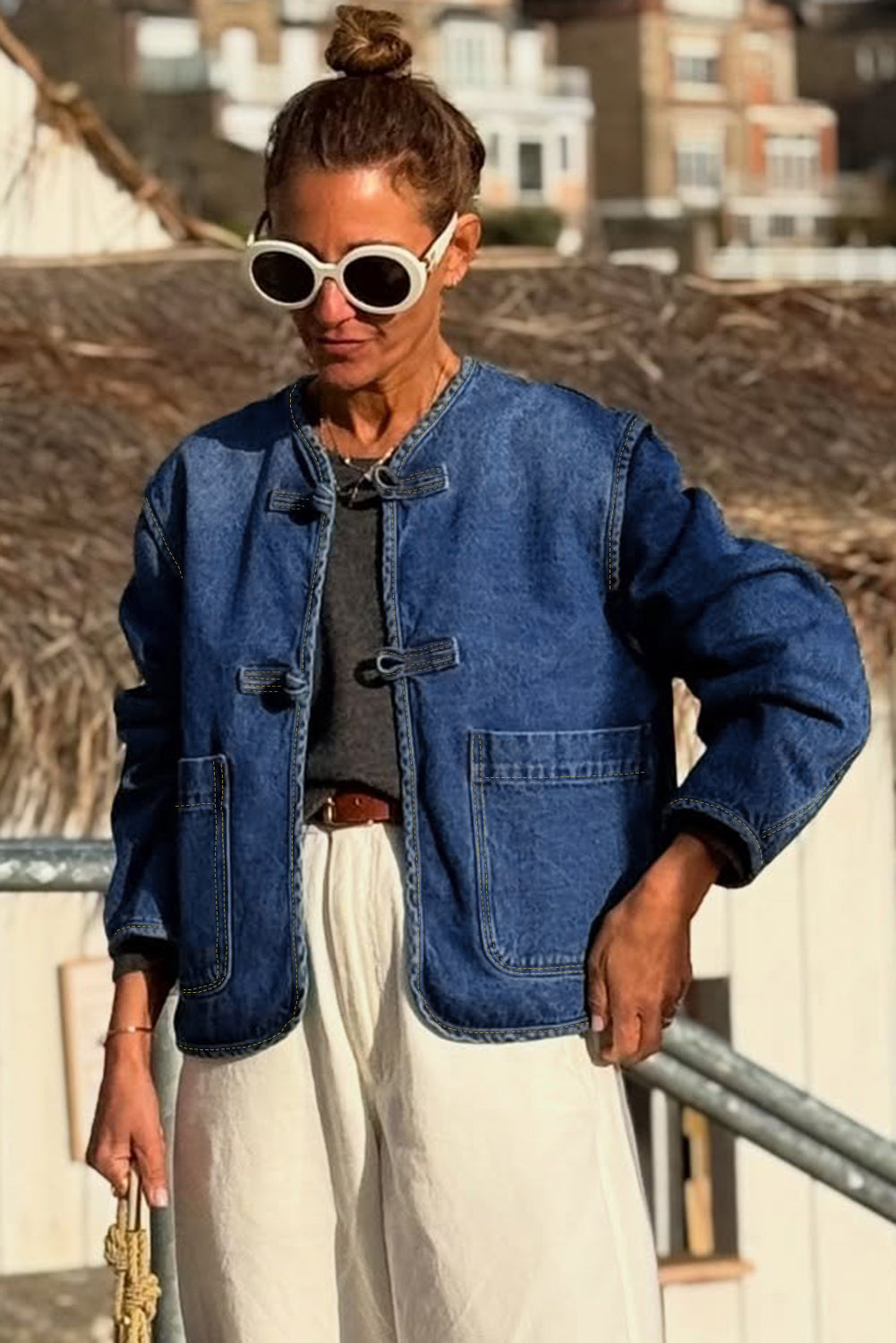 Person wearing a blue denim jacket and sunglasses outdoors.