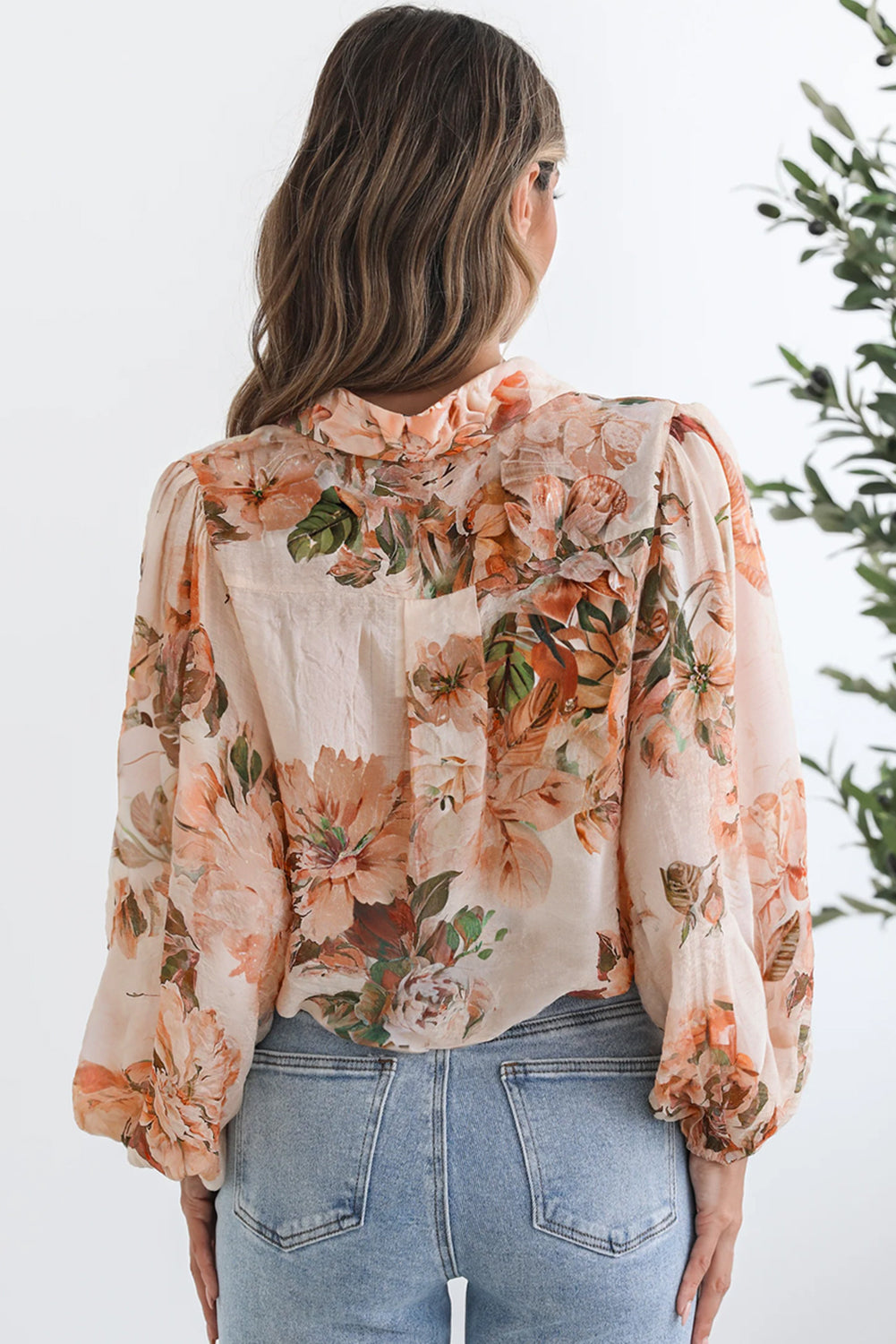 Woman wearing a floral blouse with long sleeves and a neutral background