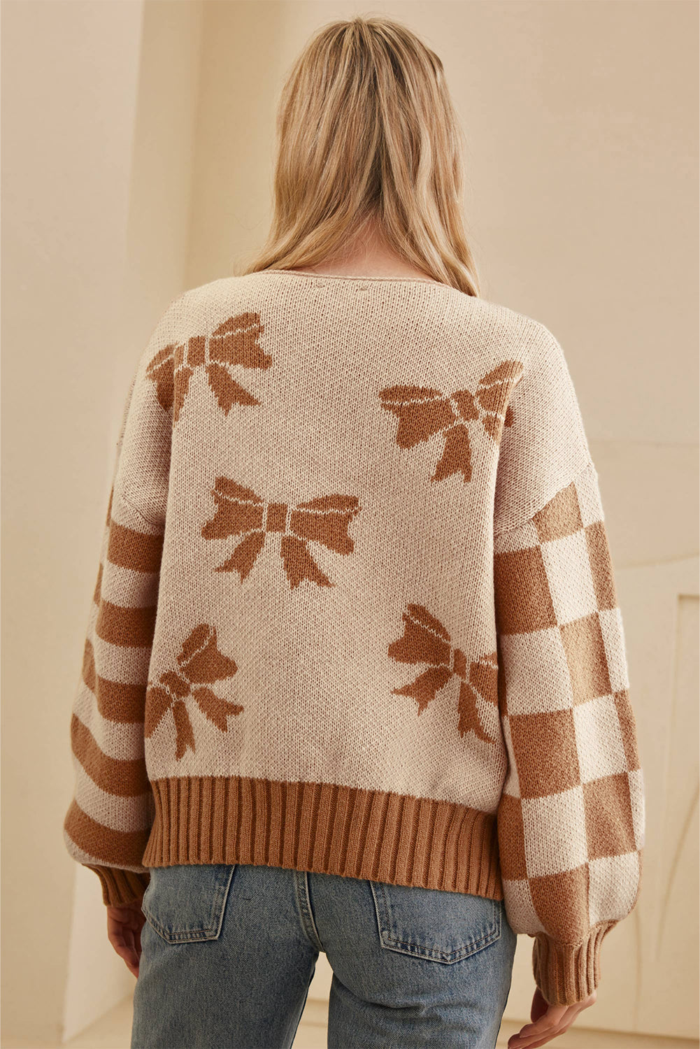 Person wearing a sweater with bow pattern in a neutral setting