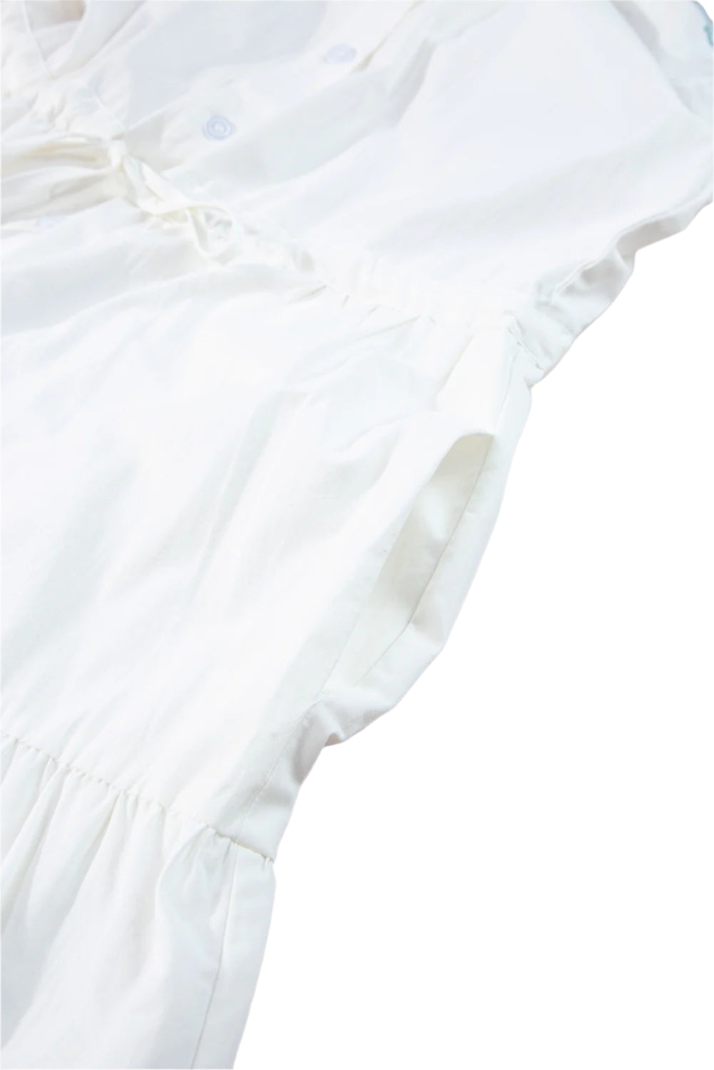 Close-up view of the pocket on a white tiered shirt dress with short sleeves, highlighting the dress's functional design.