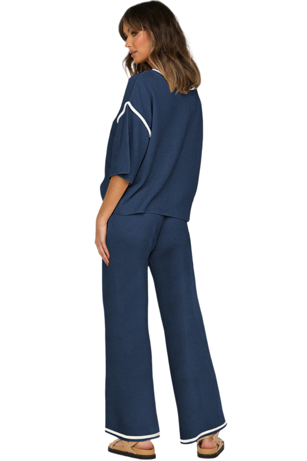 Woman wearing a navy outfit with white accents on a plain background