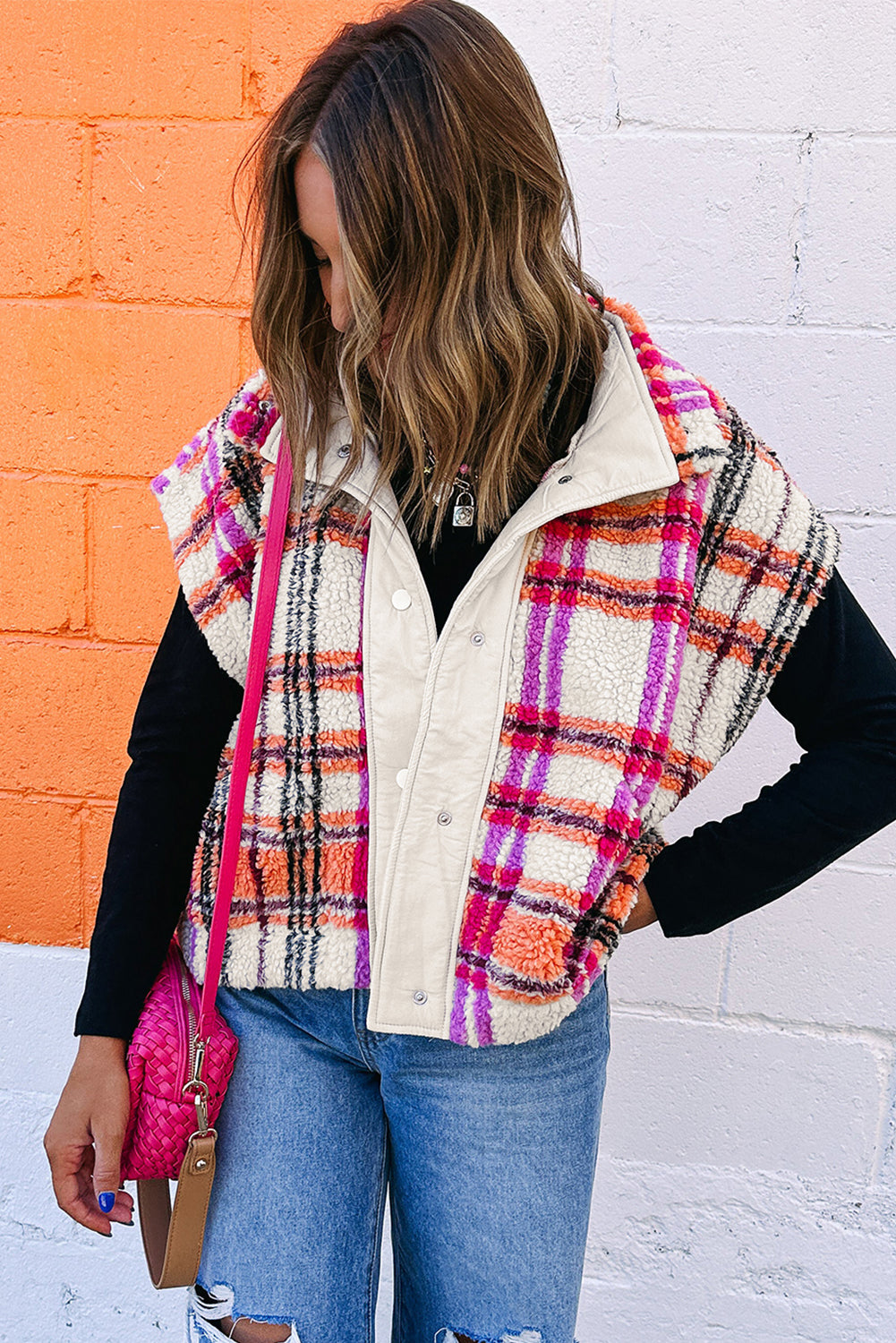 Person wearing a plaid vest over a black long-sleeve shirt with a colorful background.