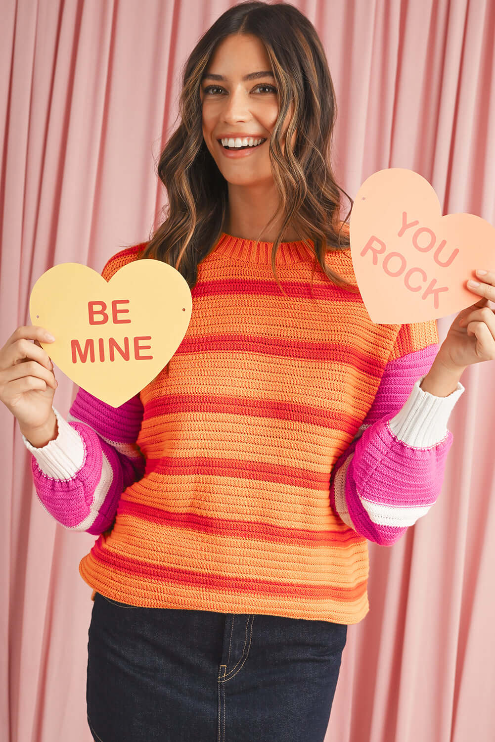 Woman wearing a colourful striped knit jumper with a relaxed fit.