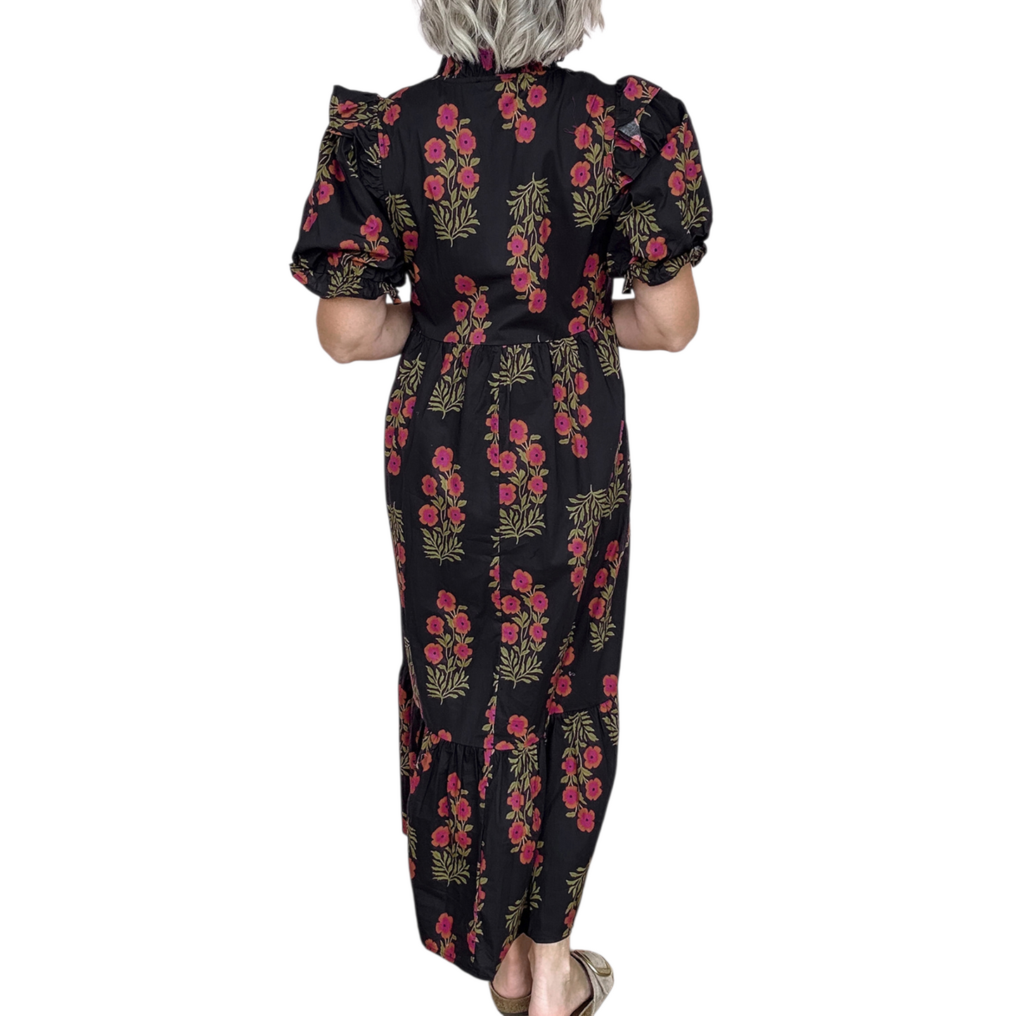 Back view of a woman wearing a black and pink floral cotton midi dress with puff sleeves and a tiered ruffle hem.