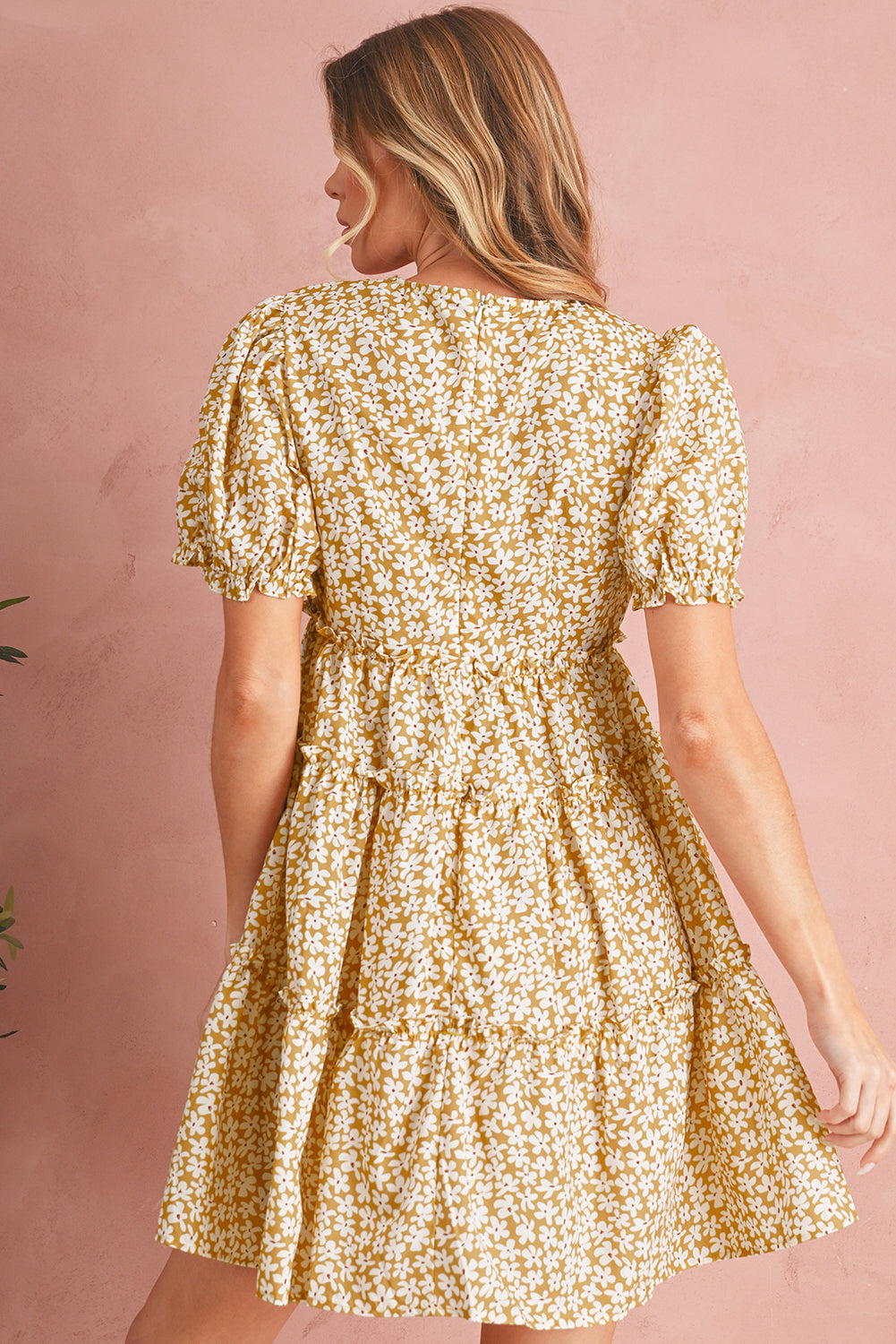 Woman wearing a gold floral dress against a pink background