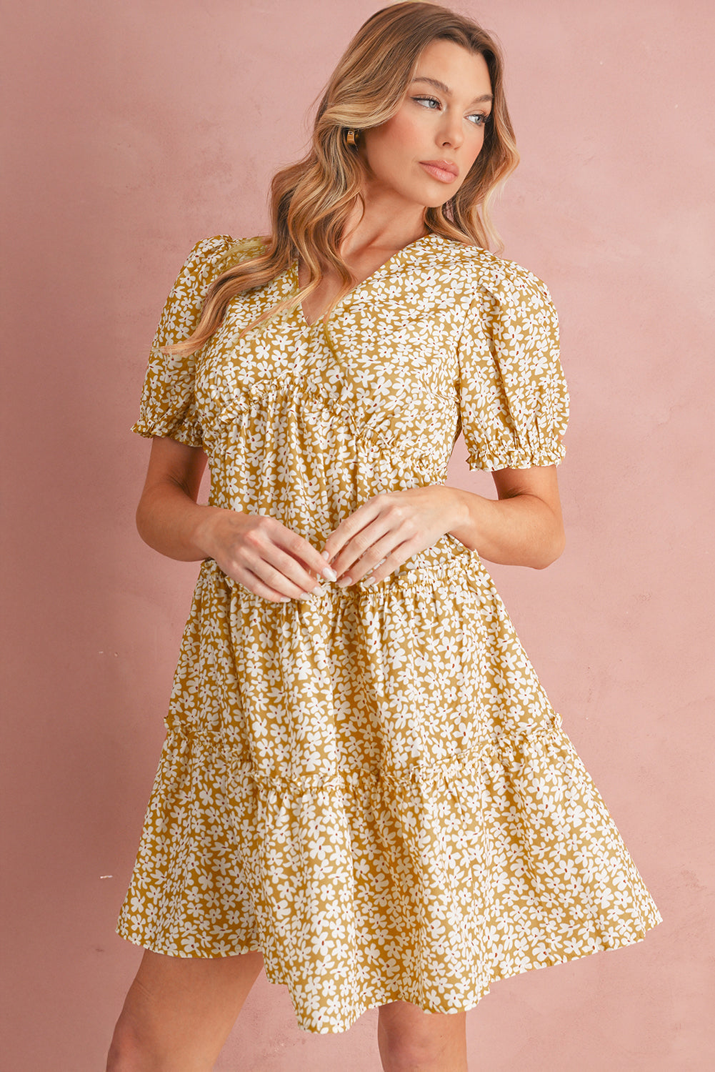 Woman wearing a yellow floral dress against a pink background
