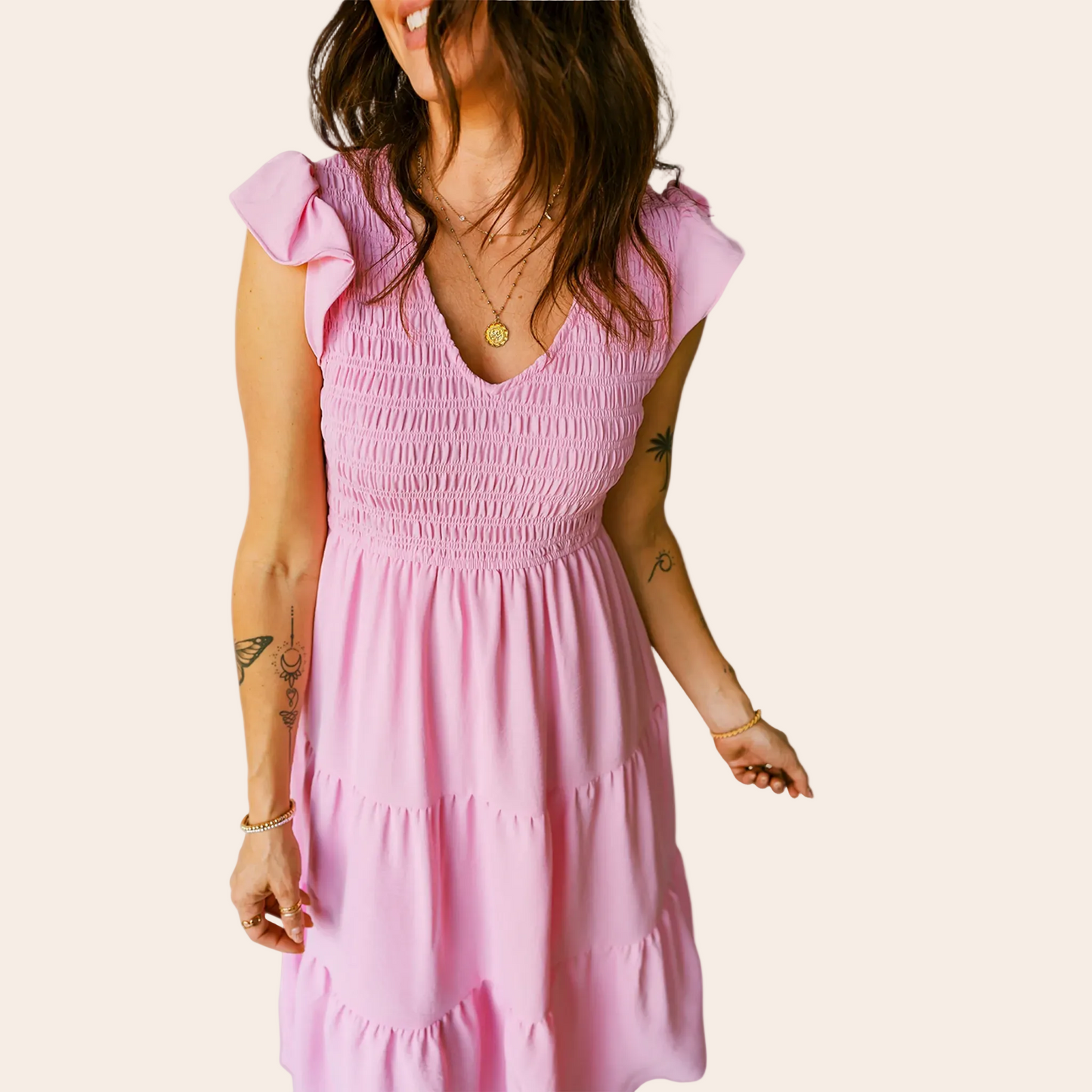 Woman wearing a pink dress with ruffled sleeves against a plain background