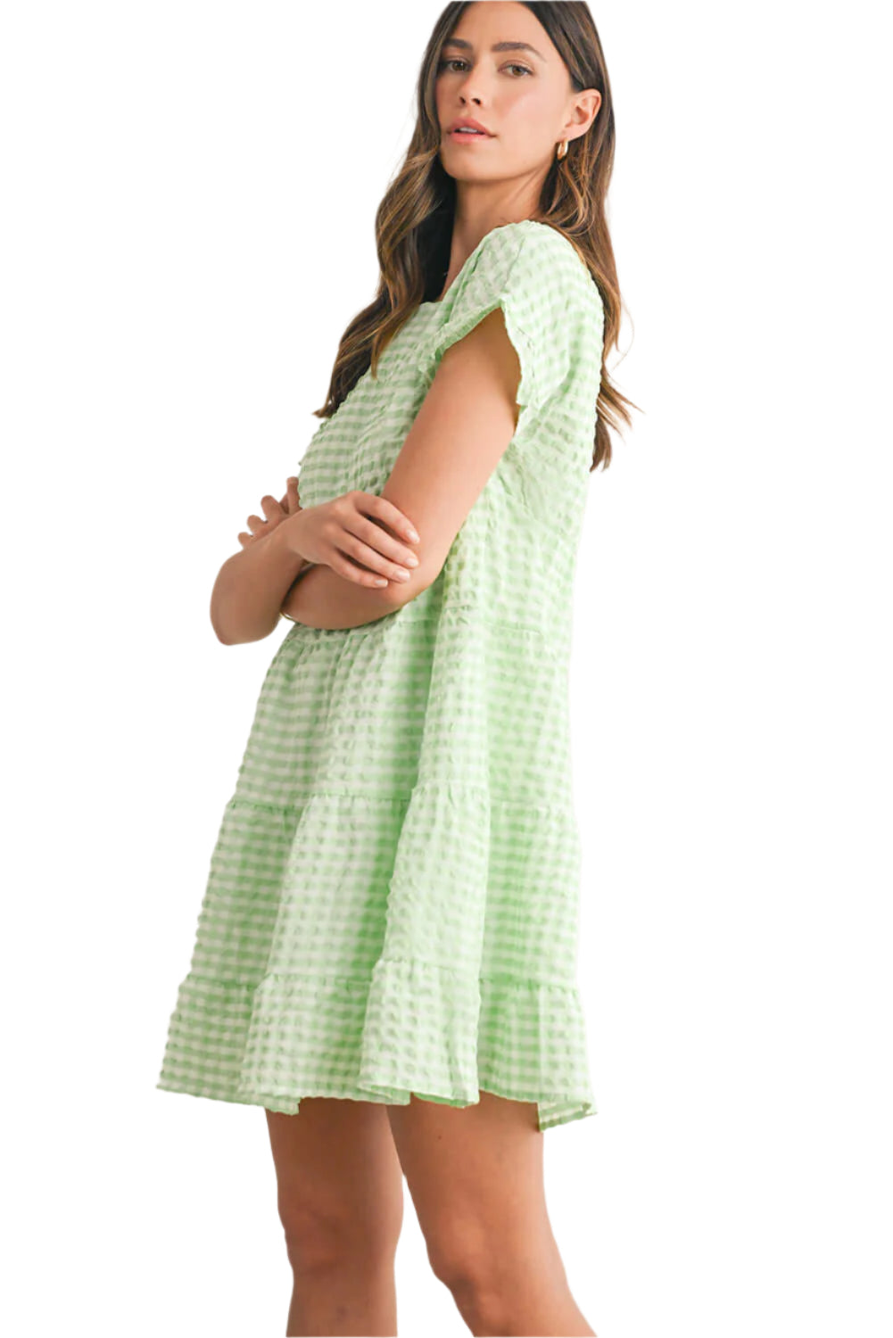 Woman wearing a light green plaid ruffle mini dress with short sleeves, ideal for summer casual occasions.
