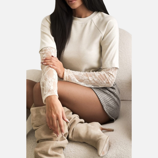 A model wearing a cream-colored top with detailed lace sleeves, paired with plaid shorts, capturing the top's texture and fit.