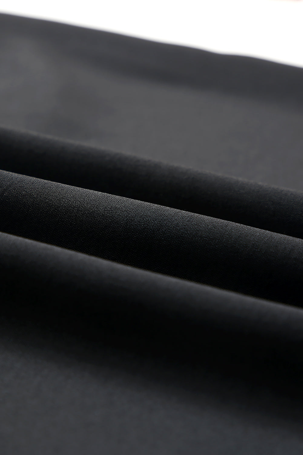 Fabric view of a ladies' black dress with soft ruffle sleeve details.