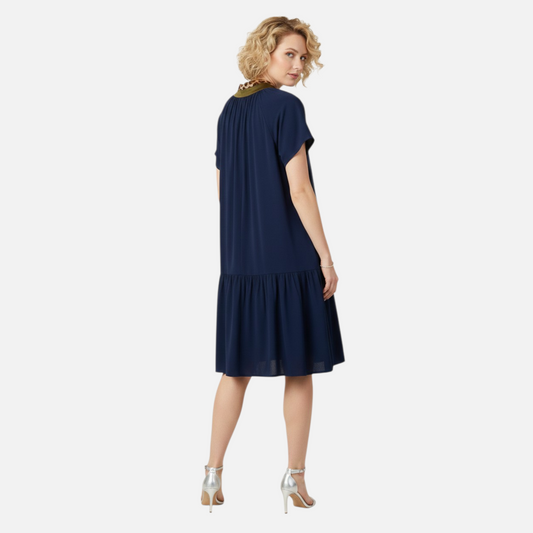 Rear view of a navy drop-waist dress highlighting the gathered ruffle hem and clean, relaxed silhouette.
