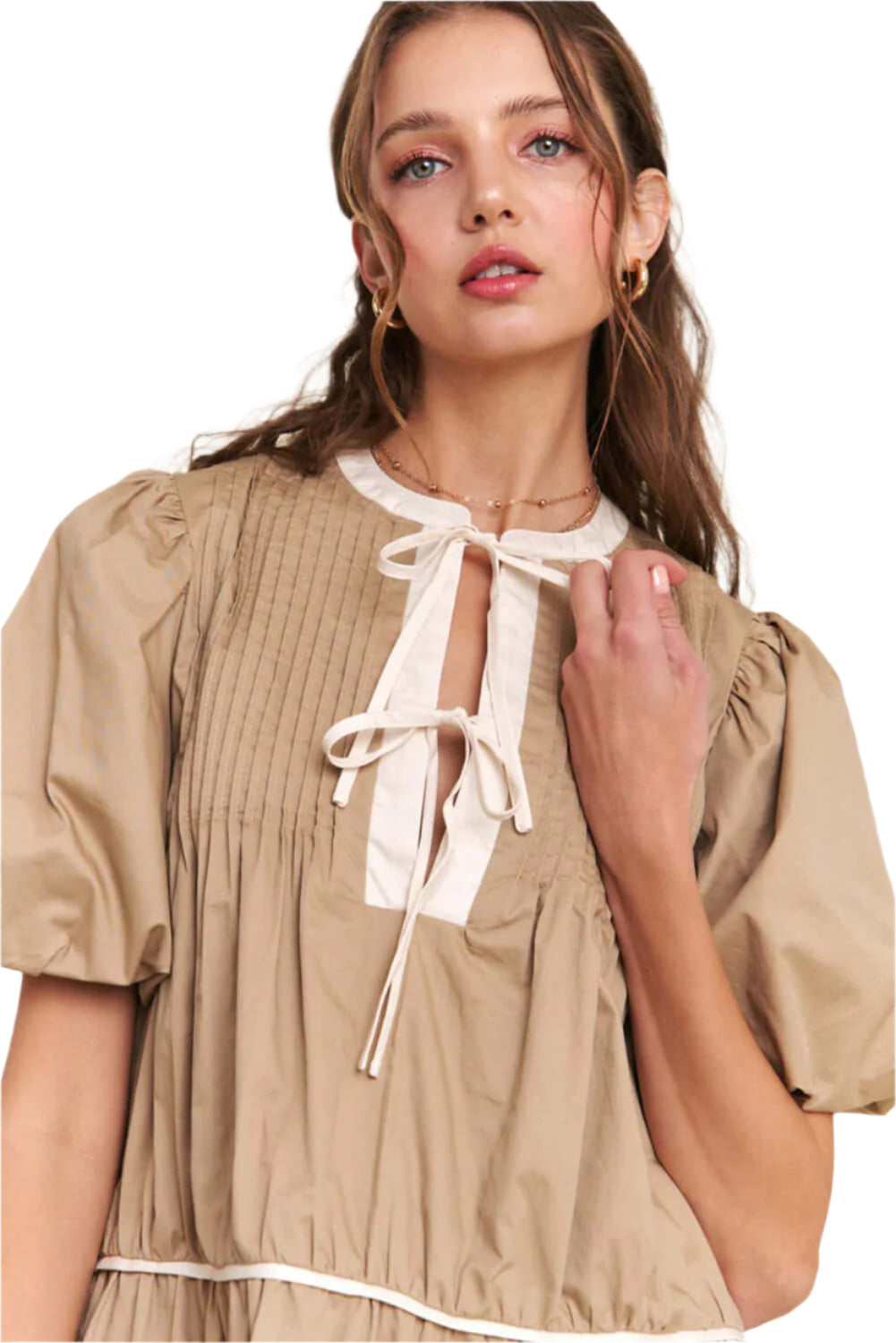 Close-up of a woman wearing a pale khaki knot front mini dress with puff sleeves, perfect for summer events and special occasions.