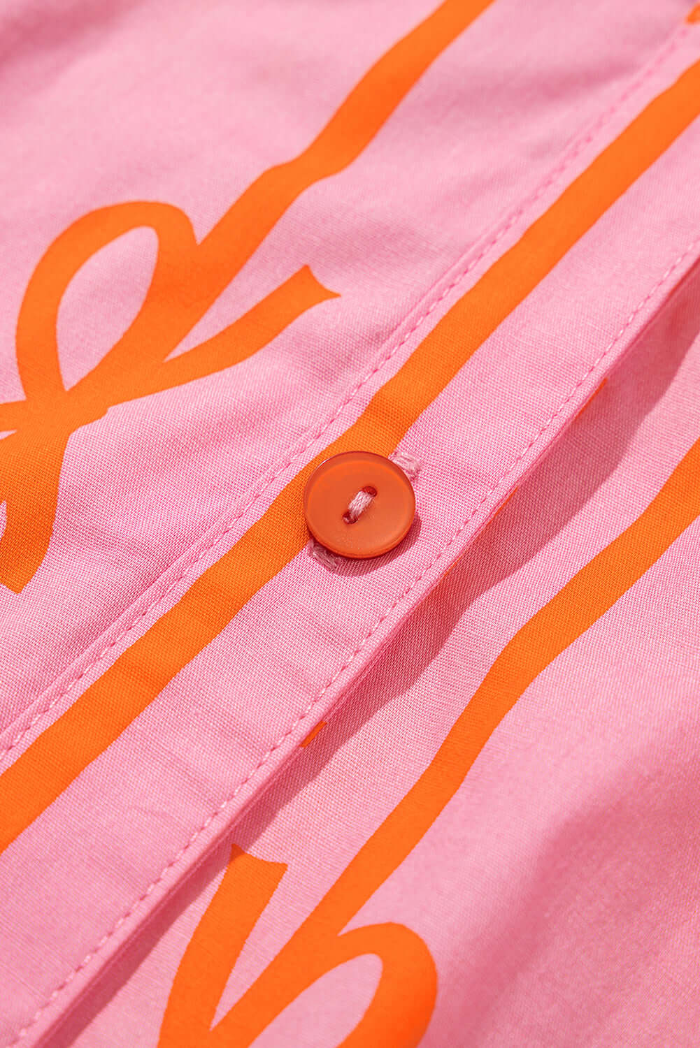 Pink mini dress with bowknot print and bubble sleeves - focus view on its button feature.