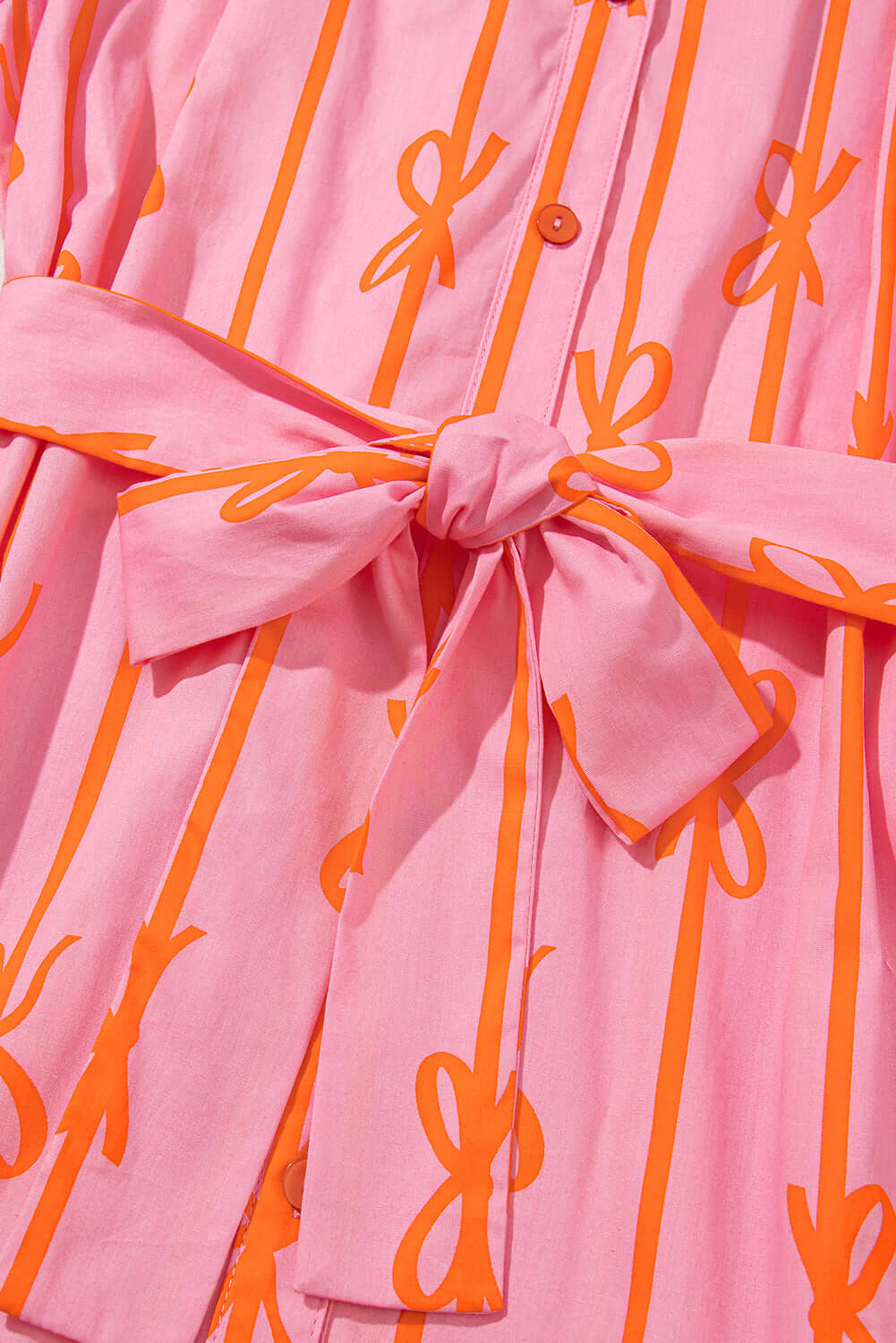 Pink mini dress with bowknot print and bubble sleeves - focus view on its waist tie feature.