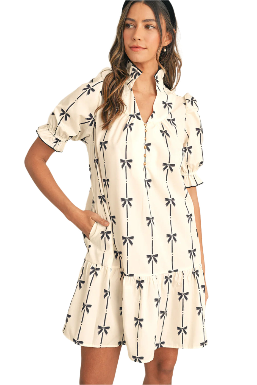 Model walking in a trendy beige mini dress with bow print, showcasing its flowy design and summer-ready look.