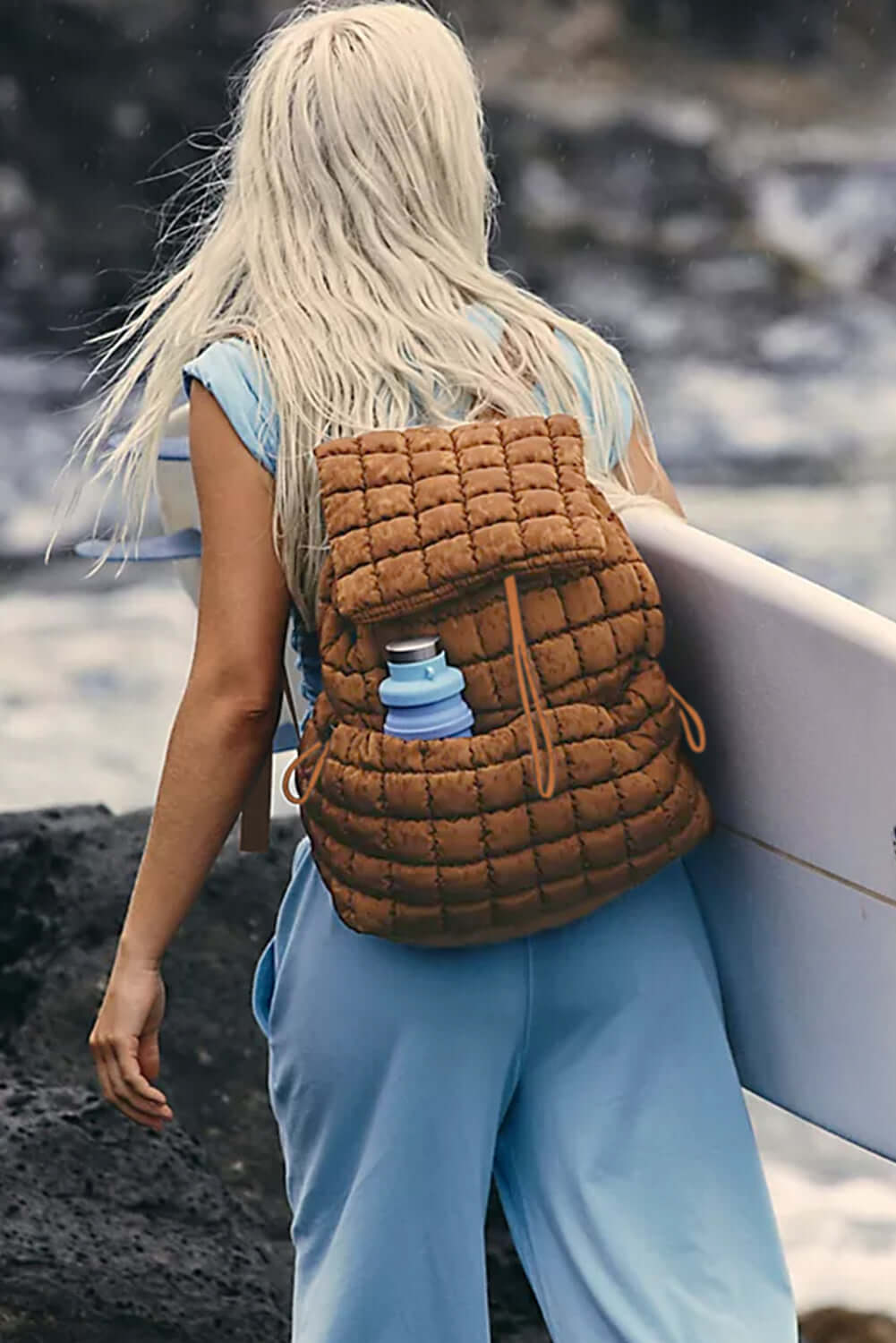 Photo of quilted puffer backpack, coffee color on the back of a woman.