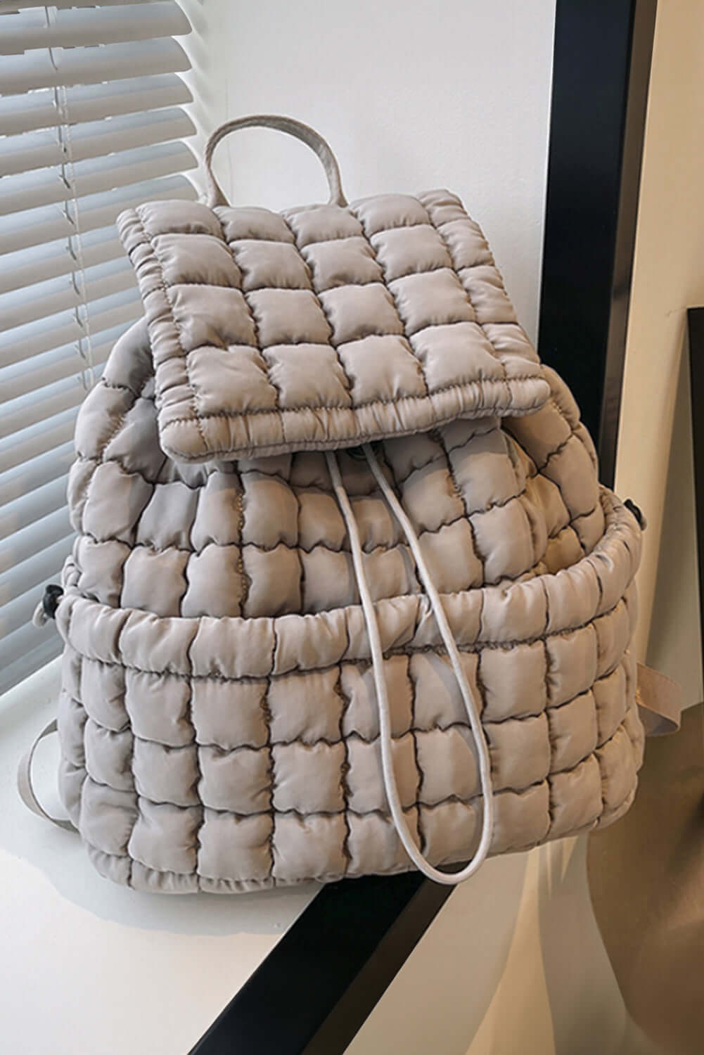 Grey quilted puffer backpack for women, versatile styling.