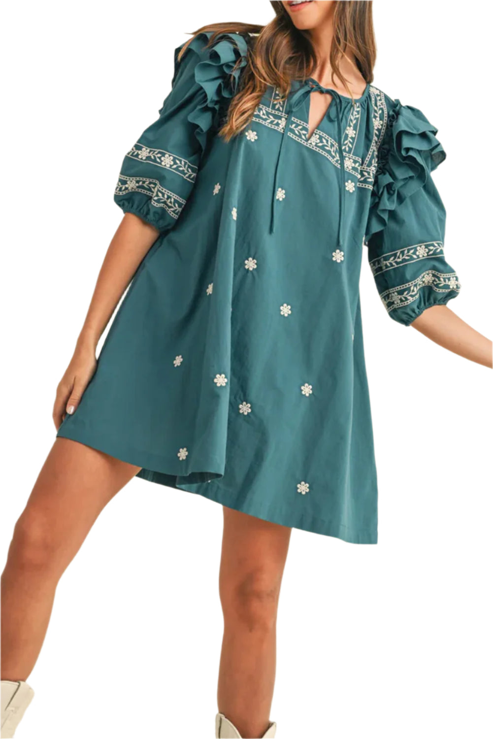 Woman wearing a teal boho mini dress with floral embroidery, puff sleeves, ruffle details, and a tie-neck design, styled for a chic and relaxed look.