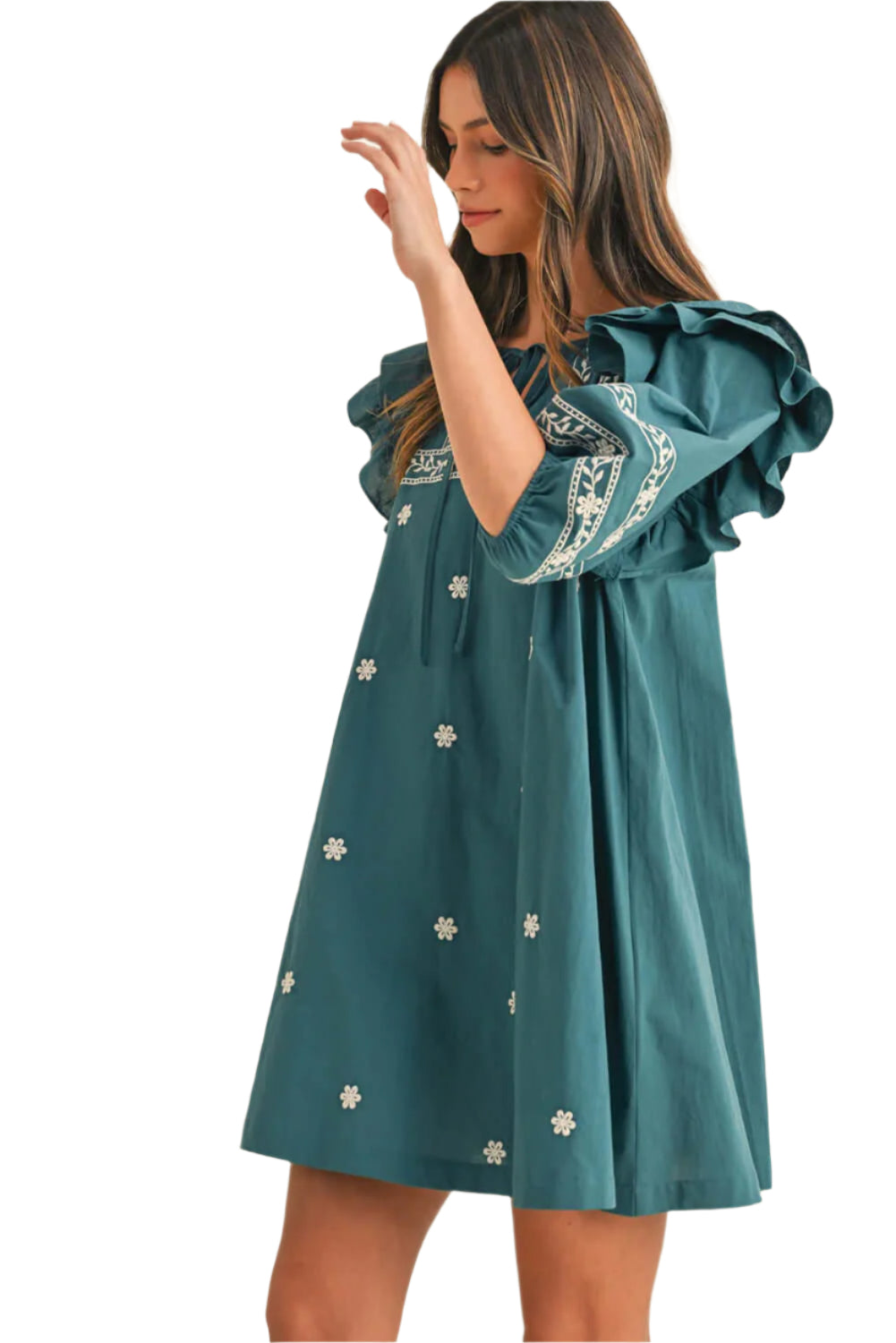 Woman in a teal boho mini dress with floral embroidery, puffed ruffle sleeves, and a tie-neck detail, showcasing a relaxed and feminine silhouette.