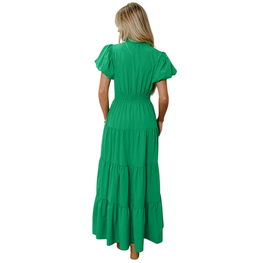 The back view of an elegant green tiered maxi dress showcasing the flowing floor-length skirt and voluminous puff sleeve detail.