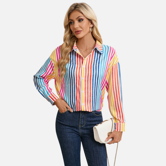 Front view of a woman wearing a vibrant vertical stripe shirt with a drop shoulder design and multicolour rainbow patterns.