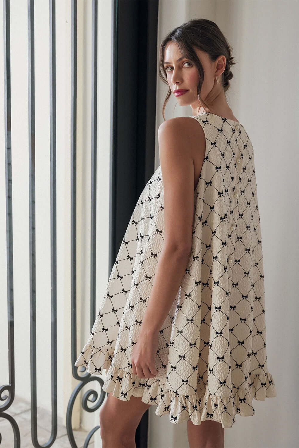 Side view of White Bow Sleeveless Mini Dress with Ruffle Hem.