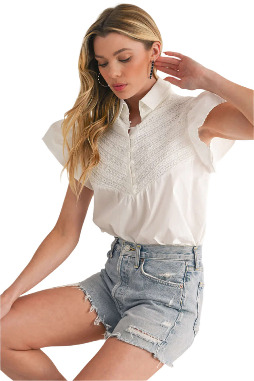 Model wearing white summer blouse with crochet accents and flared ruffled sleeves.