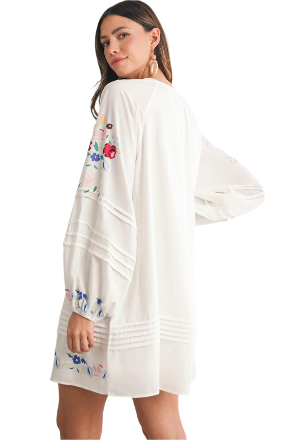 White floral embroidered boho mini dress with tassel tie neckline and flowy long sleeves. Side view.