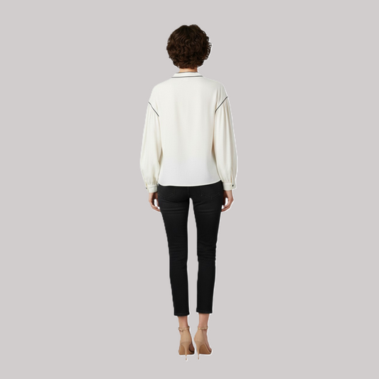 Rear lifestyle view of the cream bishop sleeve blouse paired with black denim, highlighting the draped fabric and elegant shoulder trimmings.