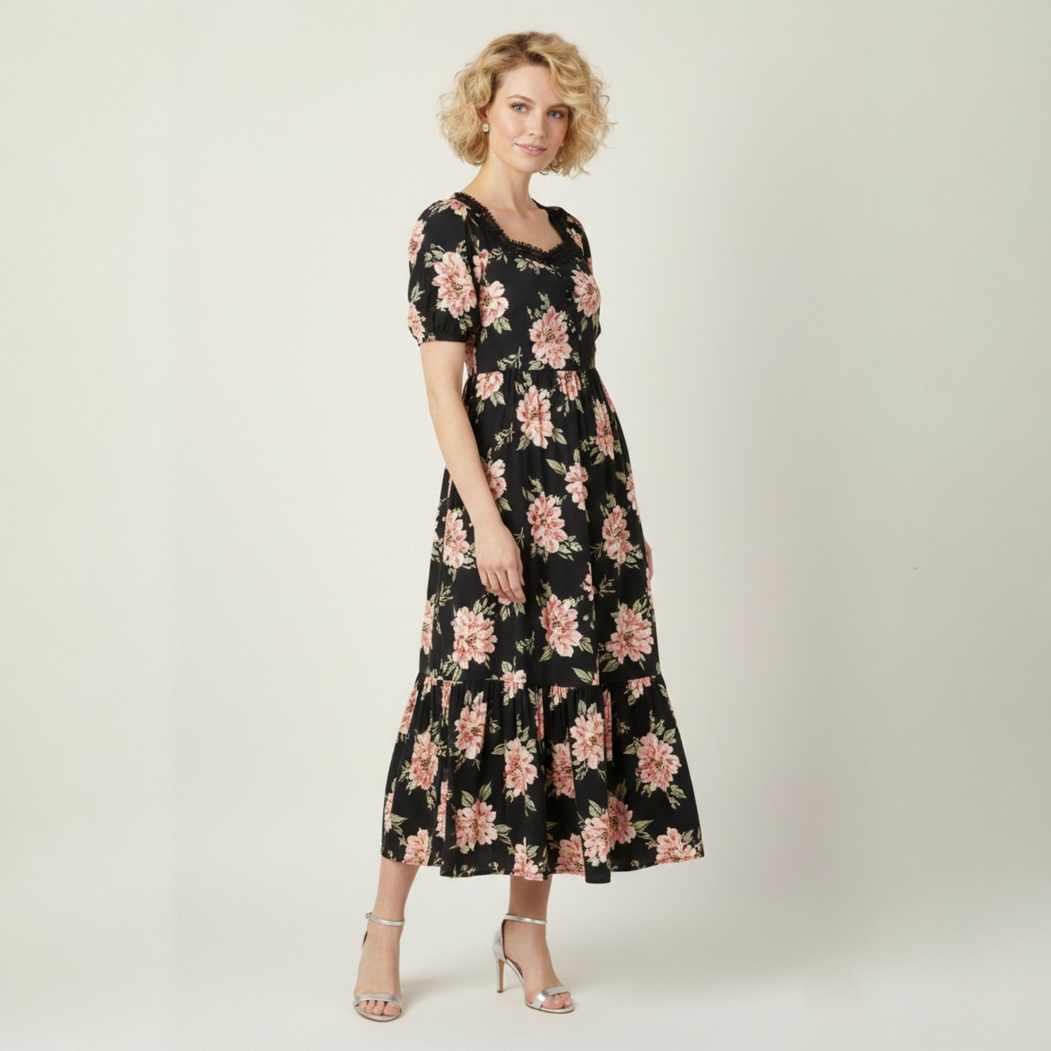 A model wearing a black short-sleeve maxi dress with a pink floral print, sweetheart neckline, and tiered hem from the Catherine Martin Women's Dresses collection.