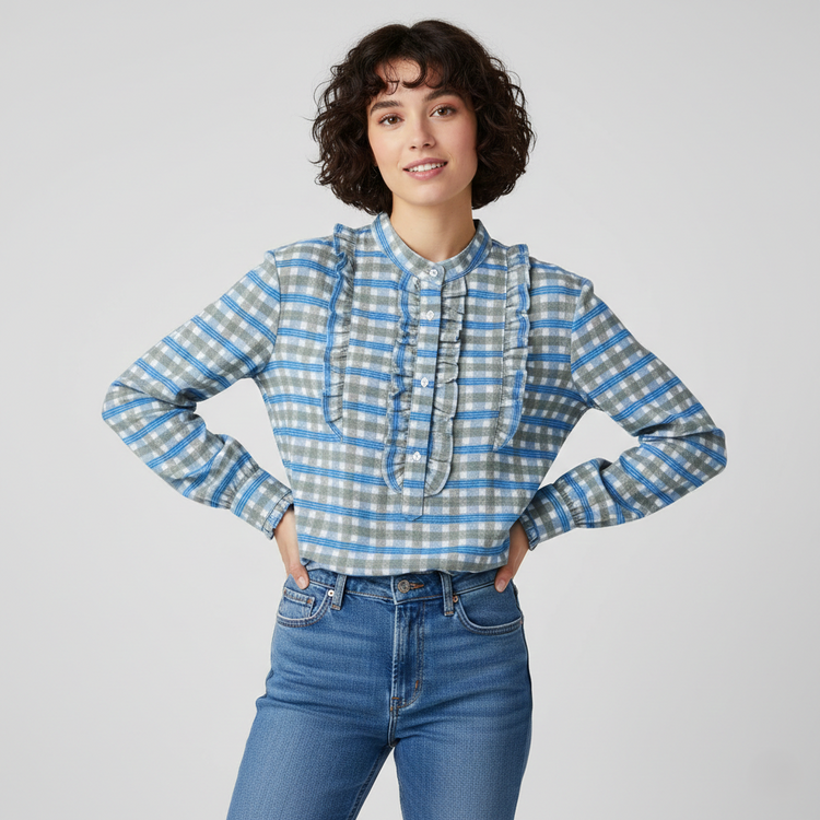 A model wearing a blue and grey plaid long-sleeve top with ruffle details from the Catherine Martin Women's Tops collection.