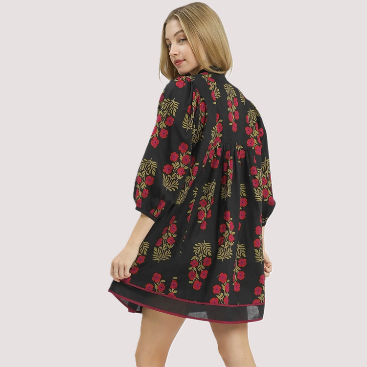 Rear view of a black floral mini dress showing a relaxed A-line silhouette, bracelet-length sleeves, and a gathered back detail.