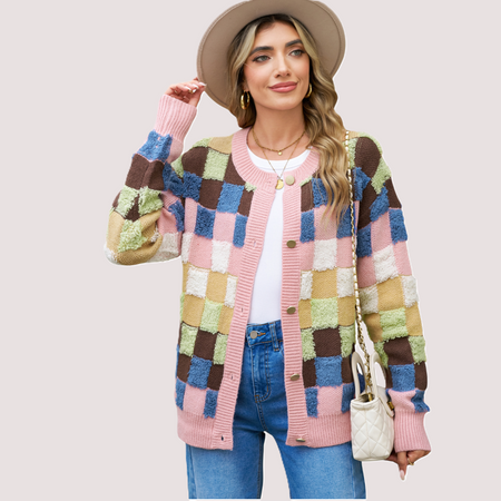 A woman wearing a modern colourblock plaid cardigan featuring textured pink, blue, brown, and olive green squares with gold-toned buttons.