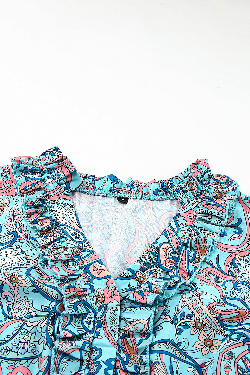 Close-up view of the neckline and fabric details of a paisley print tiered maxi dress with ruffle sleeves.