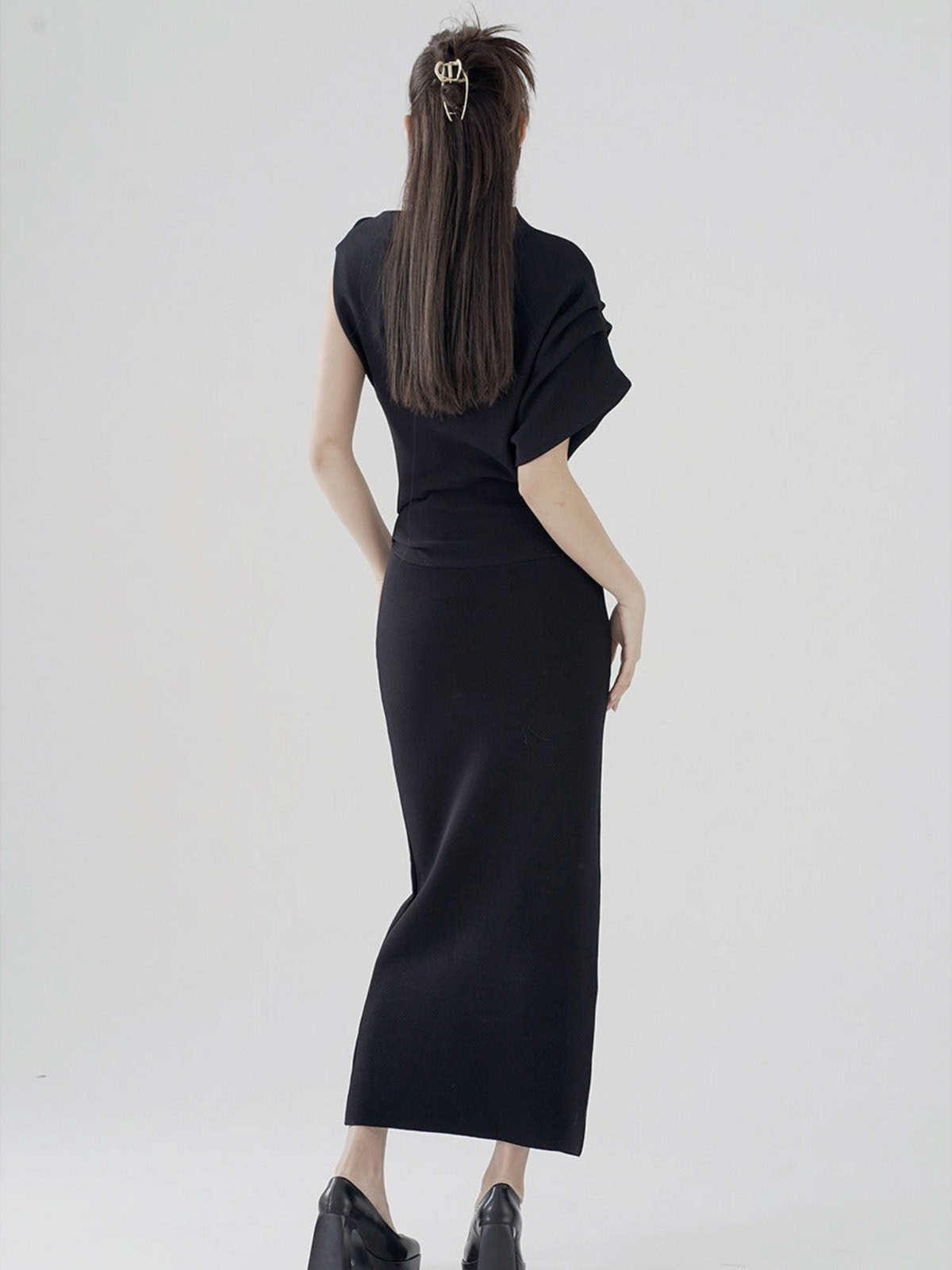 Catherine Martin black two-piece set featuring an asymmetric top with a batwing sleeve and a fitted midi skirt.