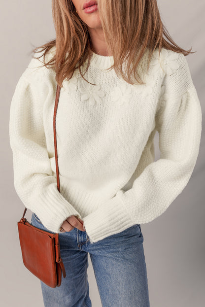 Person wearing a white sweater and blue jeans with a brown leather bag on a plain background
