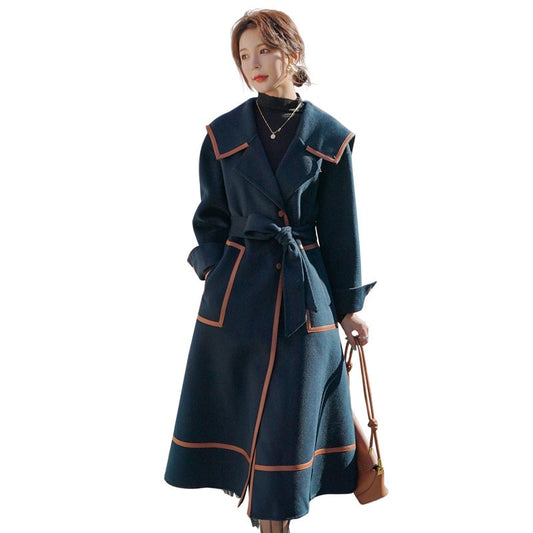 Woman wearing a long dark blue coat with pink trim on a white background