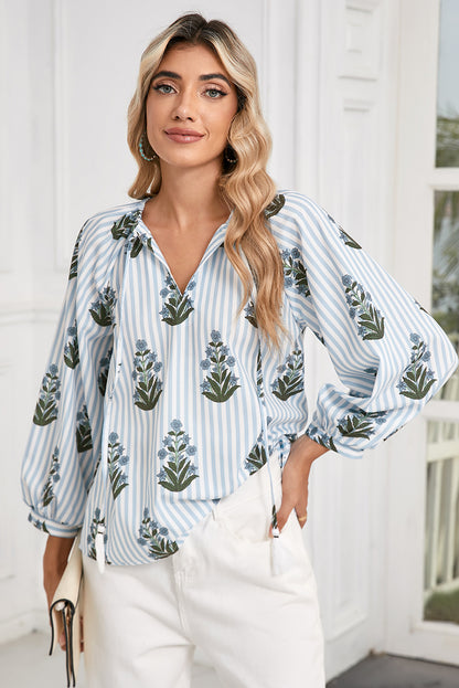 Front view of a blue floral striped blouse with long sleeves, perfect for spring and summer, worn by a model paired with white pants from Catherine Martin store.