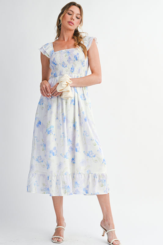 Woman wearing a floral dress holding a clutch against a white background