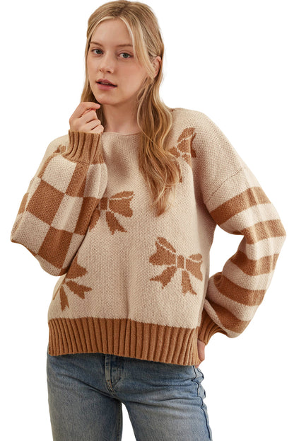 Woman wearing a beige sweater with brown bow patterns and blue jeans on a white background