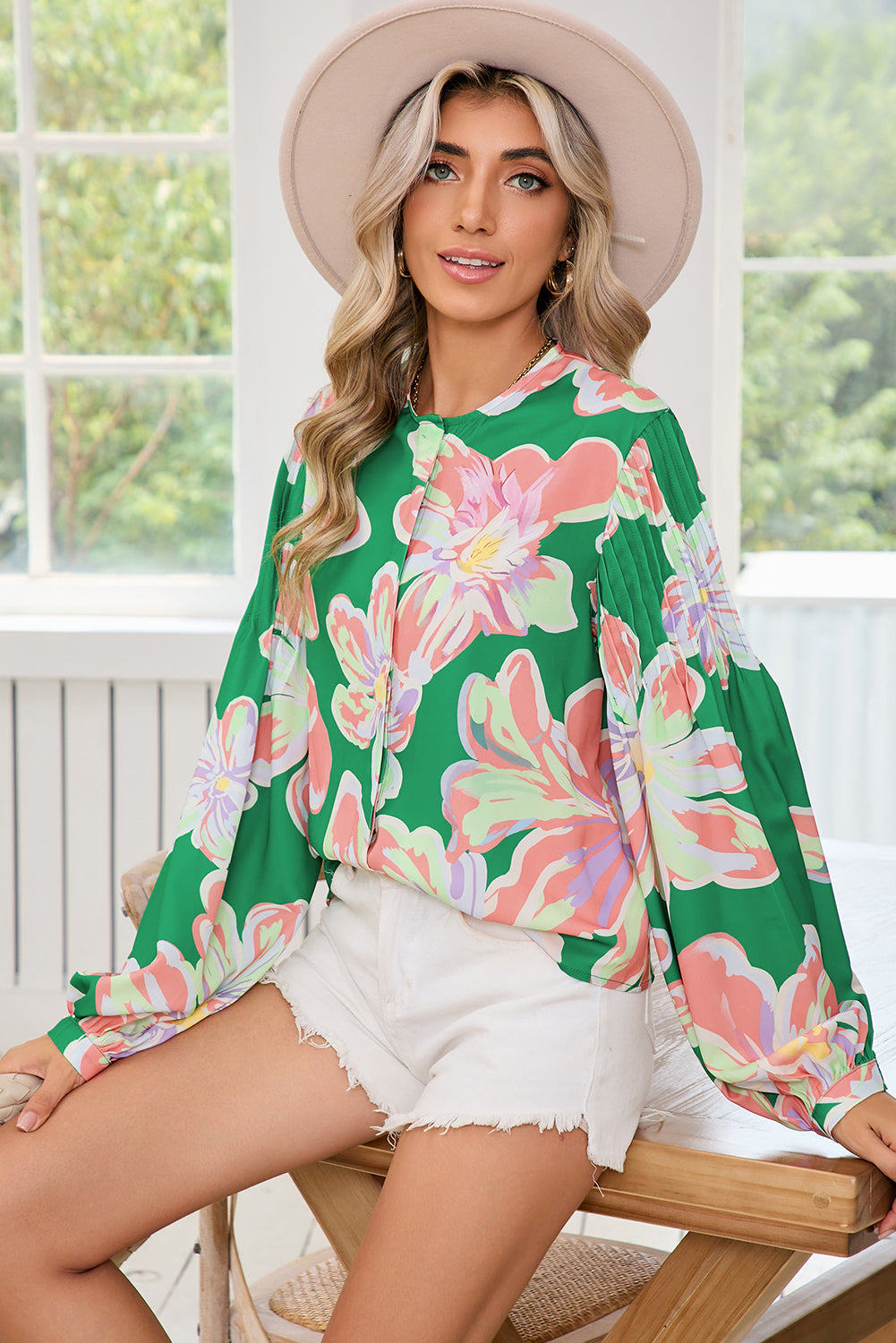 The back view of green floral blouse, featuring pleated long sleeves and front button details.