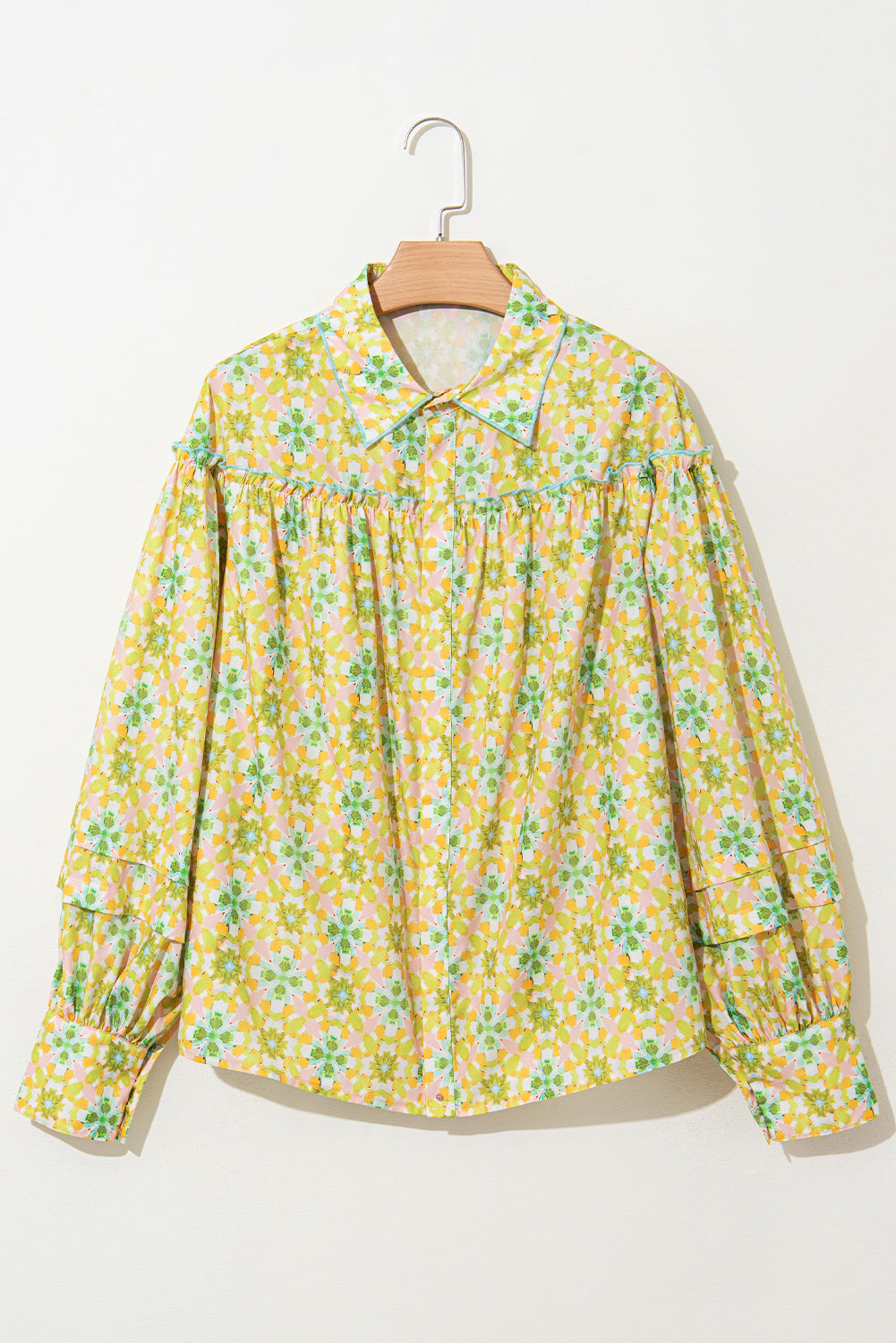 Front view of a green and yellow floral blouse with balloon sleeves on a hanger.