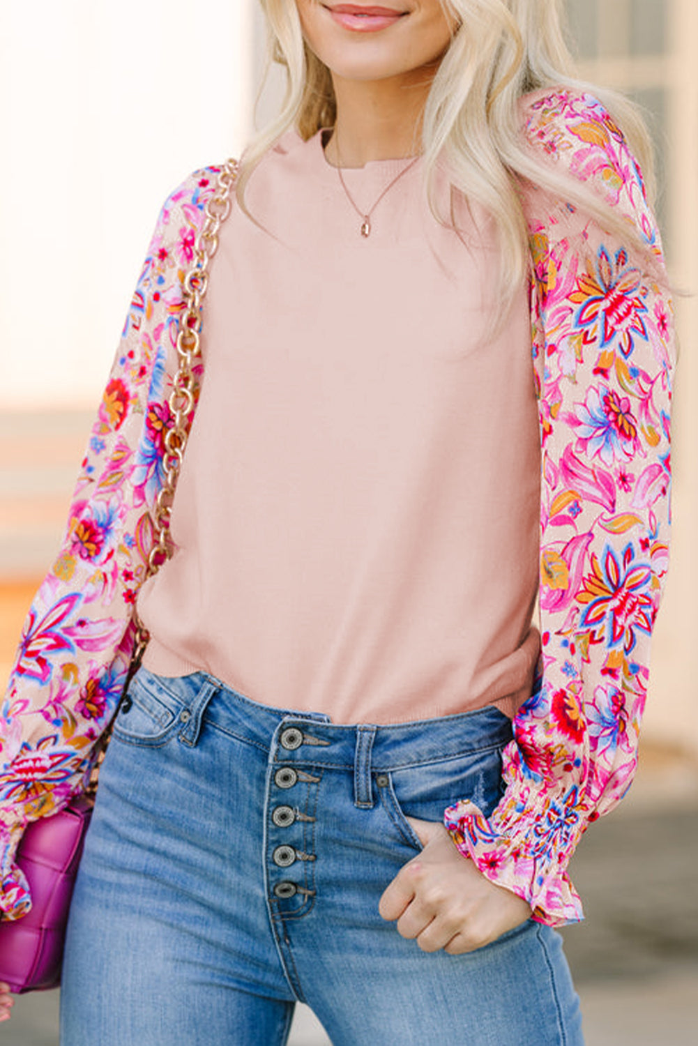 Half view of a model smiling in an oatmeal knit top with floral print long sleeves, showcasing part of her face.