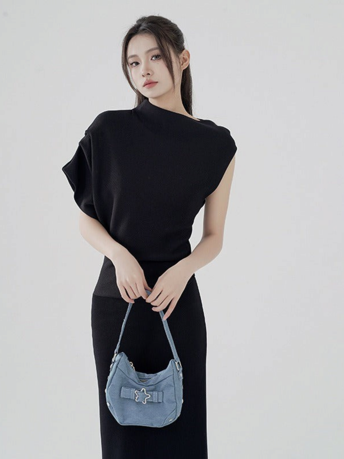 Catherine Martin black two-piece set featuring an asymmetric funnel neck top and fitted midi skirt on a model