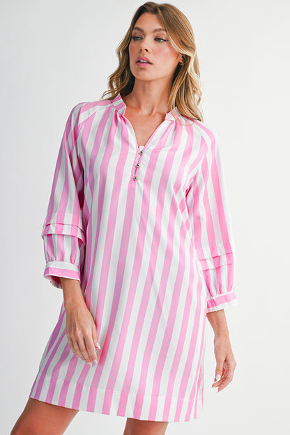 Woman wearing a pink and white striped dress against a plain background