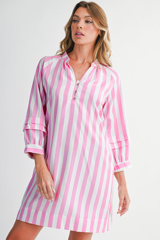 Woman wearing a pink and white striped dress against a plain background